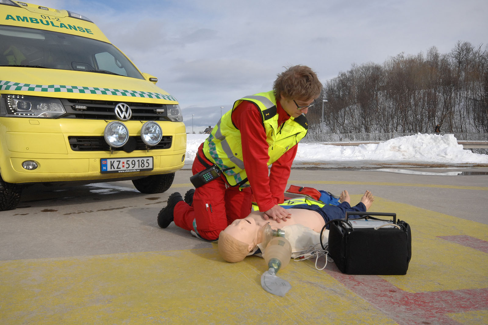 Lærling som gir førstehjelp til dukke foran parkert ambulansebil