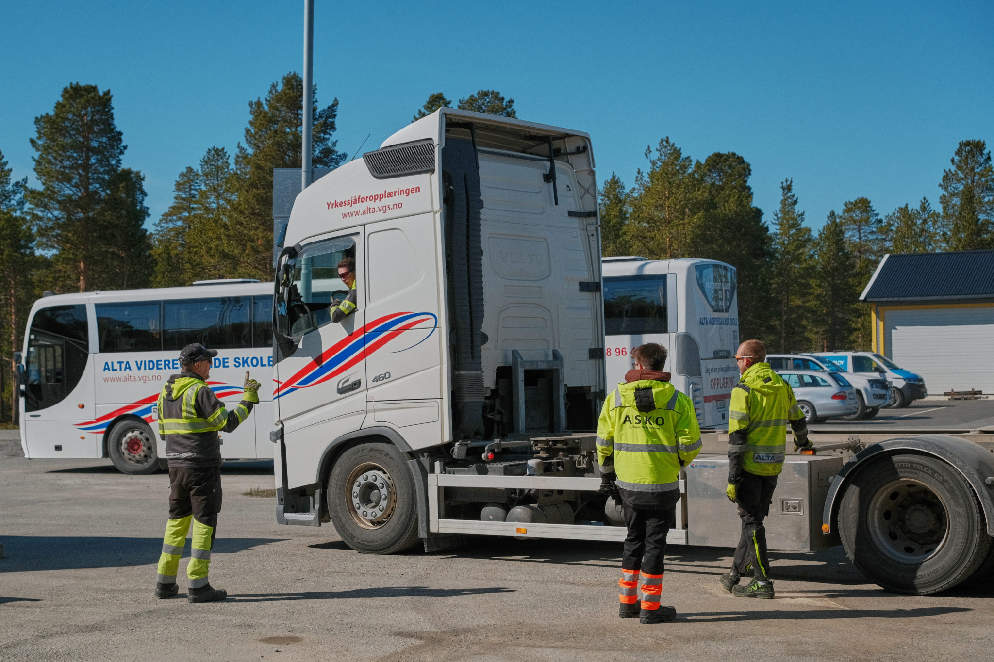 Avstandbilde av personer foran vogntog og buss i bakgrunnen